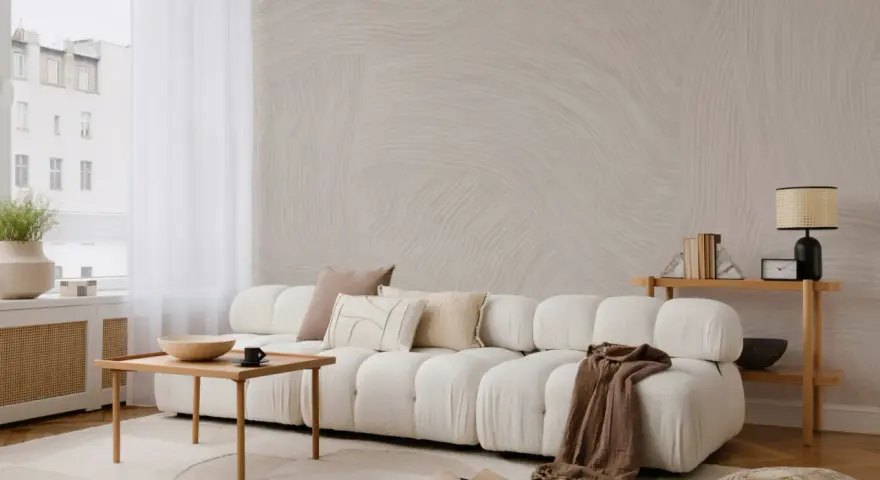 Minimalistyczny salon z sofą, stolikiem i lampą. Subtelne wzory na ścianie i dywanie podkreślają różnicę między stylem skandynawskim a japandi w oprawie eventu.