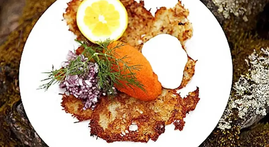 En tallrik med krispiga rårakor, serverade med rom, gräddfil, dill, rödlök och citron. Ett härligt råraka recept!