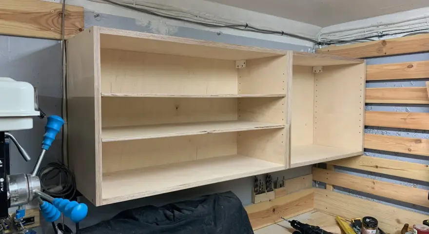 Solidne mocowanie szafek wiszących do ściany za pomocą drewnianych wsporników. Widać narzędzia i materiały do majsterkowania.