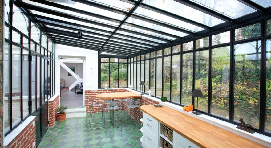 Un'idea per ampliare la cucina nella veranda: un ambiente luminoso con bancone in legno, zona pranzo e vista sul giardino.