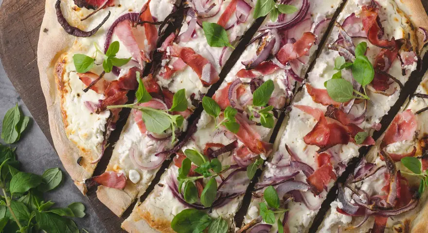 Flammkuchen mit Speck, roten Zwiebeln und frischen Kräutern – tolle Flammkuchen Belag Ideen für jeden Geschmack.