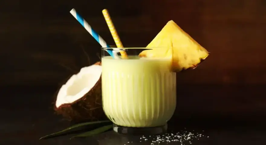 Orzeźwiający drink z mlekiem skondensowanym, ananasem i kokosem, ozdobiony słomkami. Idealny na tropikalne popołudnie.