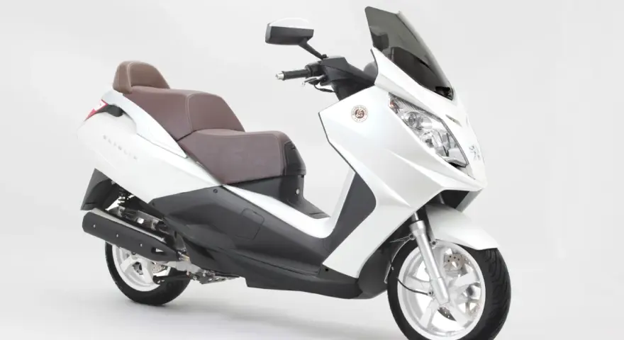 Biały skuter Peugeot Satelis z brązową kanapą, gotowy na miejskie przygody.