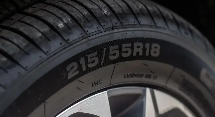 Zbliżenie na bieżnik opony z widocznym oznaczeniem 215/55R18.