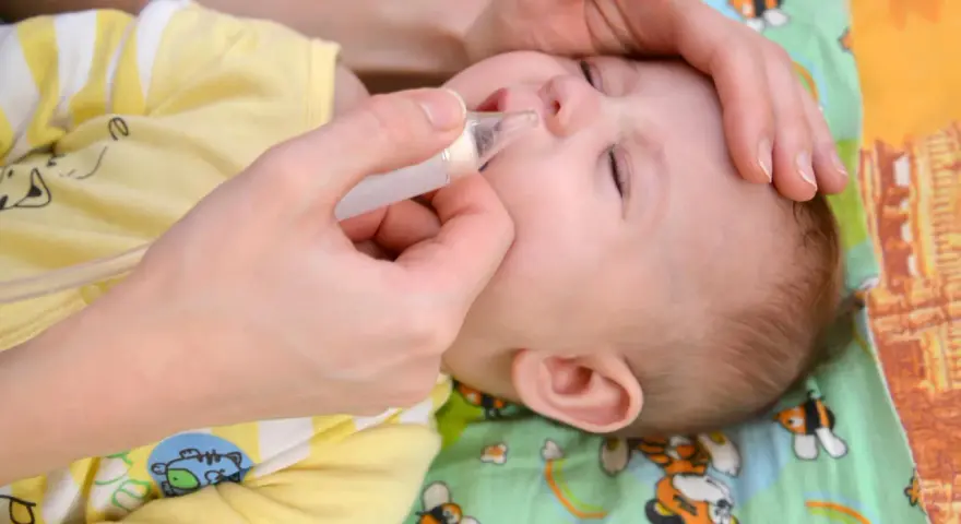 Mano che usa un aspiratore nasale su un neonato con naso chiuso senza muco.