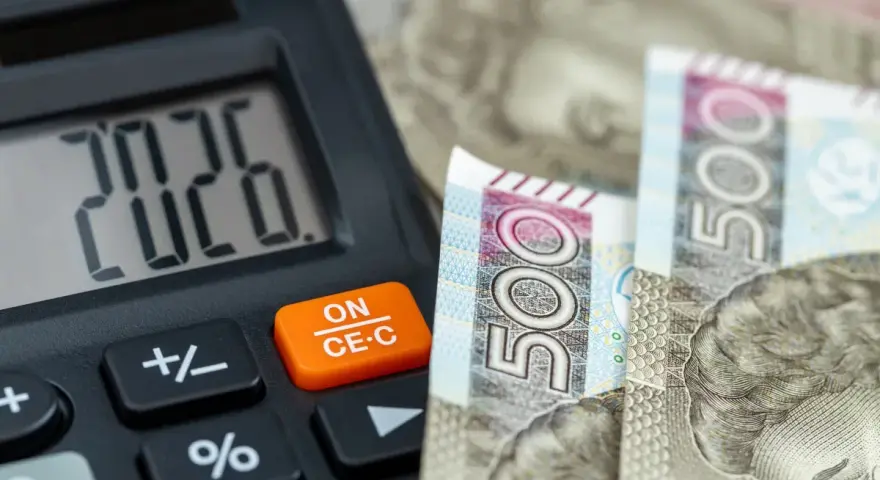 Kalkulator pokazuje 20,26, a obok leżą banknoty 500 zł. To może być odpowiedź na pytanie, ile zarabia pomocnik dekarza na godzinę.