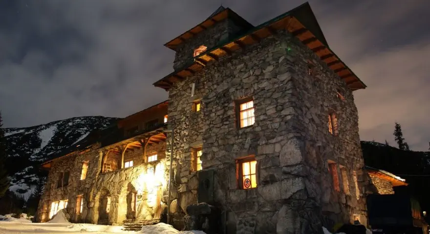Kamienny murowaniec wysokosc, oświetlony nocą, otoczony śniegiem.