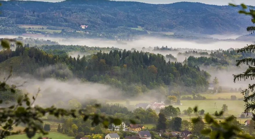 Mgliste poranki nad Sudetami. W oddali widać zamek, a niżej rozciągają się lasy i urokliwe miejscowości.
