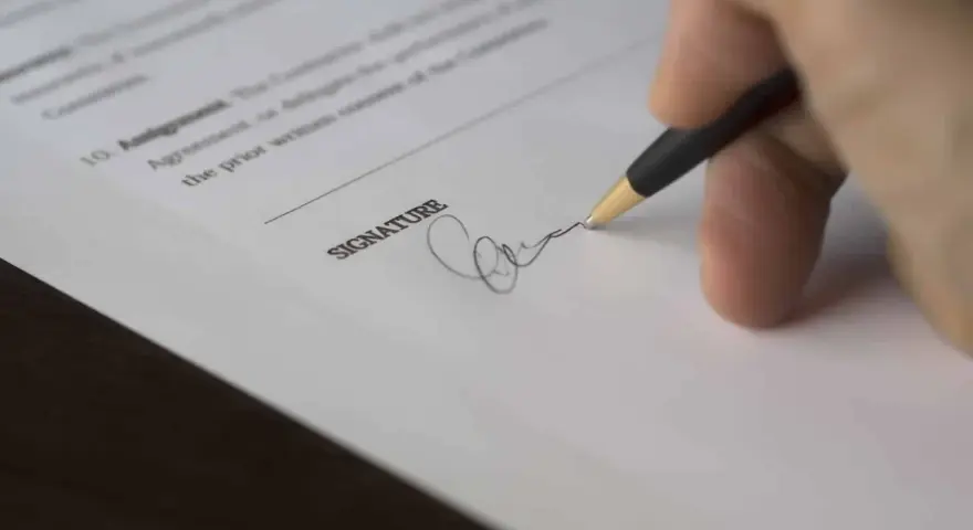 Dłoń podpisuje dokument, być może odpowiedź na pozew wzór.