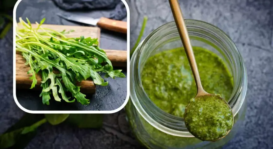 Un mazzetto di rucola fresca su un tagliere e un barattolo pieno di vibrante pesto di rucola, pronto per insaporire i tuoi piatti.