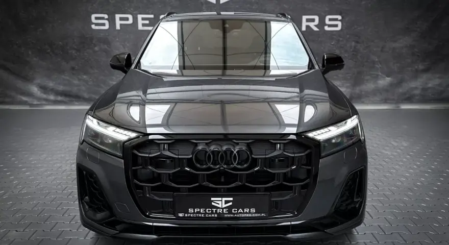 Przód ciemnoszarego Audi Q7 z czarnym grillem i światłami LED.