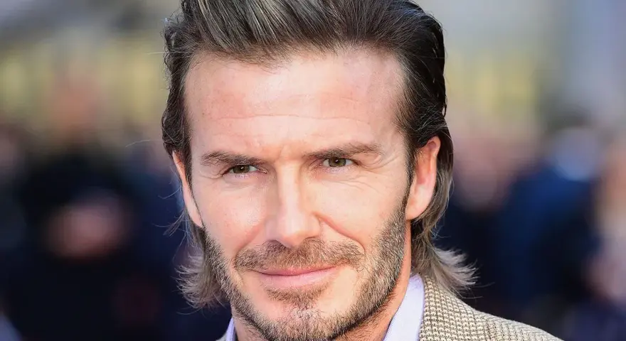 Hombre con pelo semi largo hombre liso, barba cuidada y traje a cuadros.