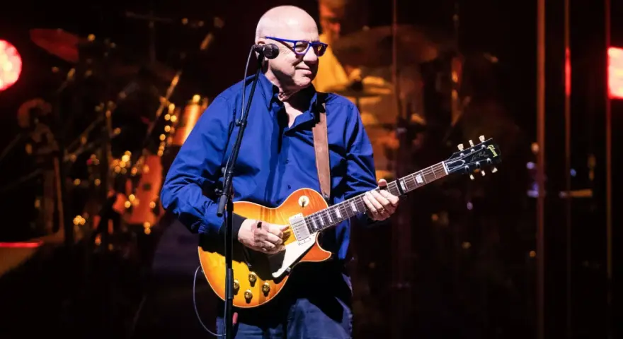 Mark Knopfler na scenie, grając na gitarze Gibson Les Paul. Jego charakterystyczne utwory brzmią w tej chwili na żywo.