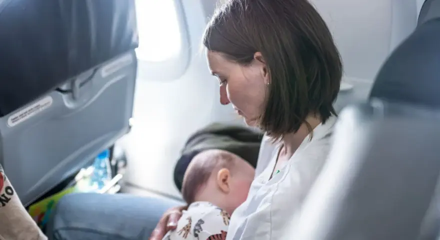 Mamma allatta il suo neonato di 6 mesi in aereo, un momento intimo durante il viaggio.
