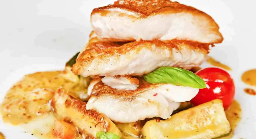 Piatto di pesce impanato e fritto, servito con verdure e salsa. Un'ottima scelta per il tuo menu di pesce.