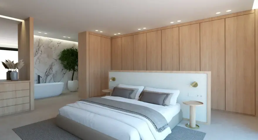 Elegante dormitorio con armarios de madera clara y detalles blancos. La cama, con ropa de cama blanca y cojines grises, se combina perfectamente con la pared de mármol y la bañera.
