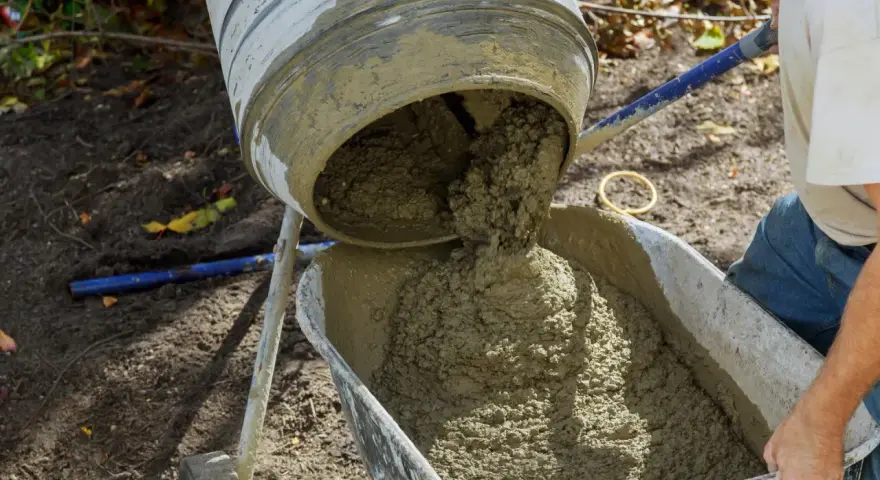 Betoniarka wylewa świeży beton do taczki. Oto jak zrobić beton w wiadrze, gdy potrzebujesz go do małych prac.