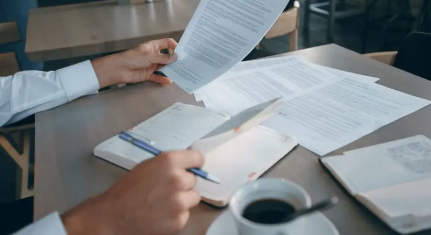 Mężczyzna analizuje dokumenty, szukając informacji o e-sądzie i nakazie zapłaty. Co dalej? Kawa i notatnik czekają.