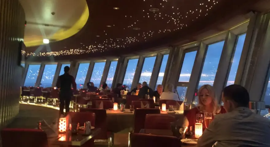 Gemütliches Alexanderplatz Restaurant mit Sternenhimmel-Decke und Panoramablick auf die Stadt bei Nacht.