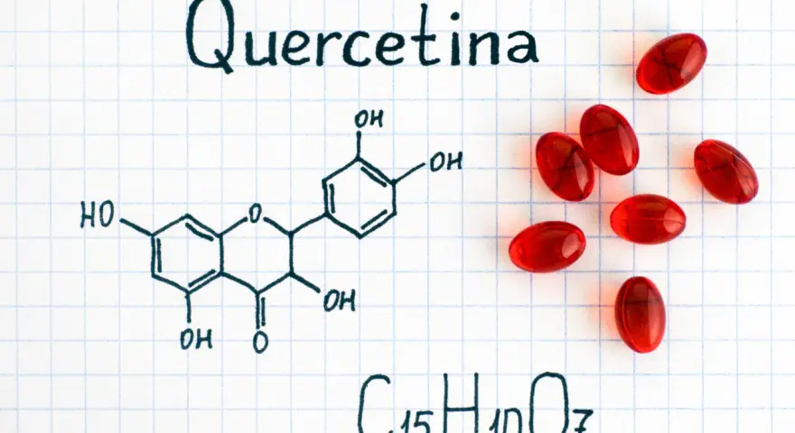 Fórmula química de la quercetina, un flavonoide con propiedades antioxidantes, junto a cápsulas rojas.
