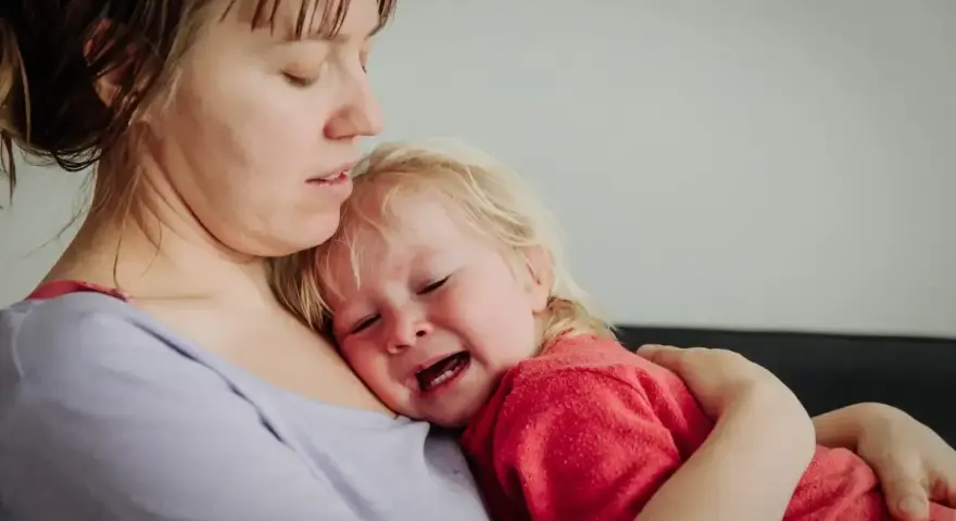 Mama tuli 2-latka, który płacze, przytula go mocno.