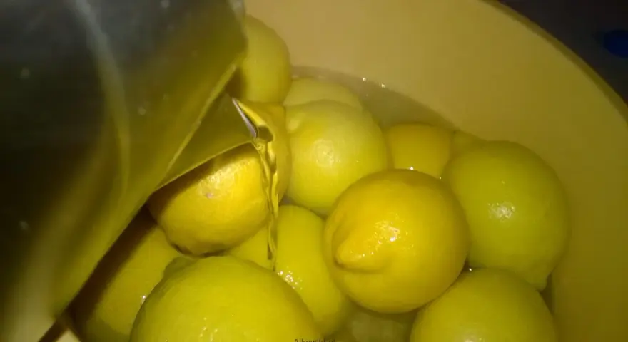 Woda z cytrynami w misce, przygotowanie do zrobienia wódki cytrynowej. Przepis na domową nalewkę.