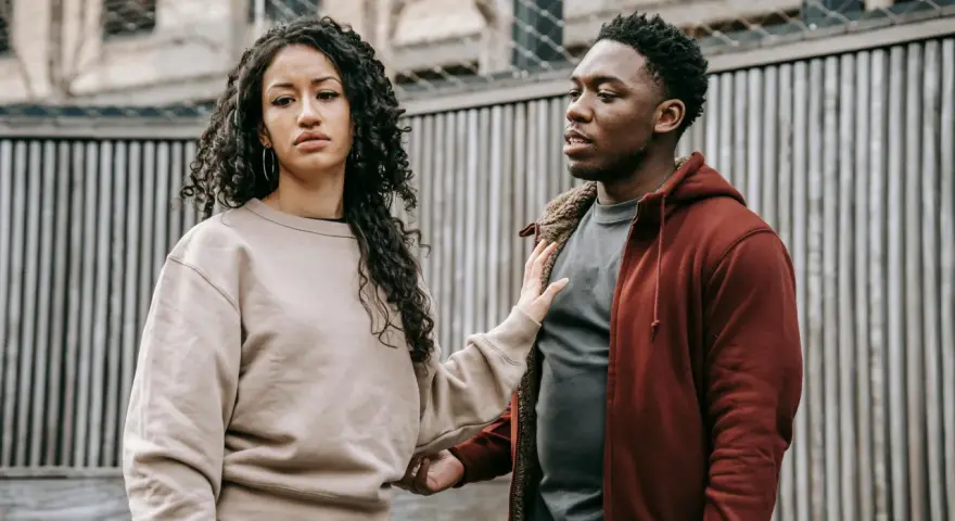Un homme et une femme se regardent, l'air préoccupé. Sa main sur son bras suggère une tentative de connexion, mais son expression montre qu'il ne veut plus donner de nouvelles, quel effet sur les hommes.