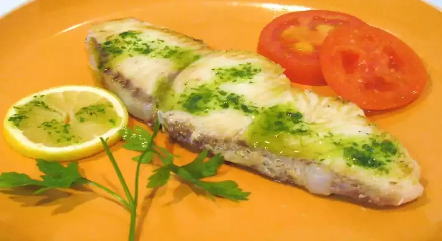Marrajo a la plancha con perejil y limón, acompañado de rodajas de tomate fresco.