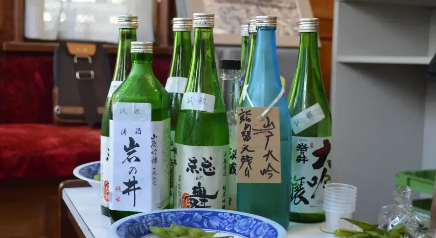 Butelki z japońskim alkoholem, idealne, gdy szukasz, czym zastąpić sake. Obok miseczka z edamame.