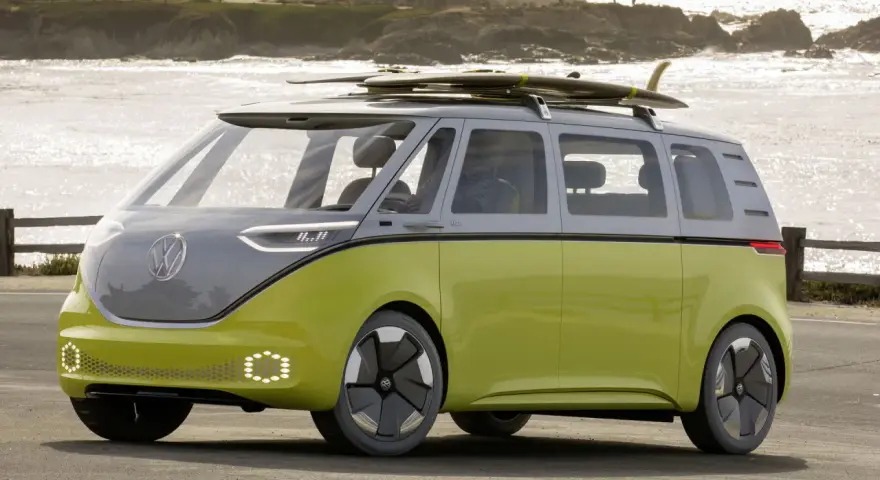 Volkswagen ID. Buzz w kolorze limonkowym z deskami surfingowymi na dachu, nad morzem.