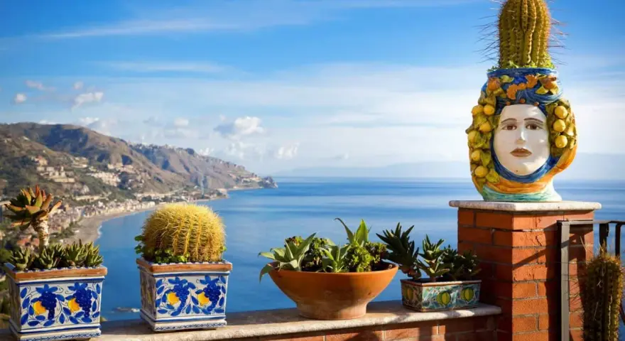 Balcone fiorito con vista sul mare, uno dei luoghi più belli della Sicilia. Cactus e piante grasse adornano la terrazza con vista sulla costa.