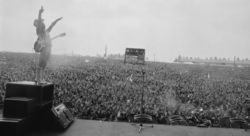 Ogromny tłum na koncercie Metallica Moskwa 1991. Wokalista na scenie, ręce w górze, wita fanów.