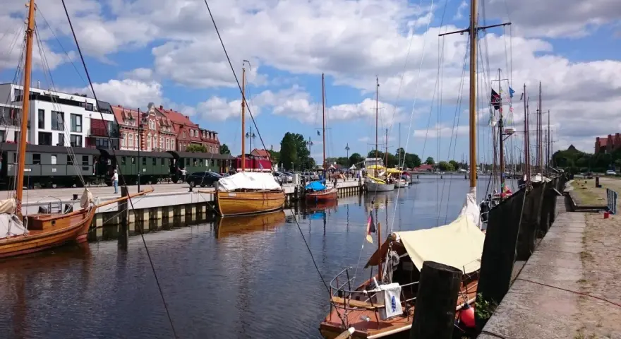 Boote im Greifswald Hafen liegen neben historischen Zügen.