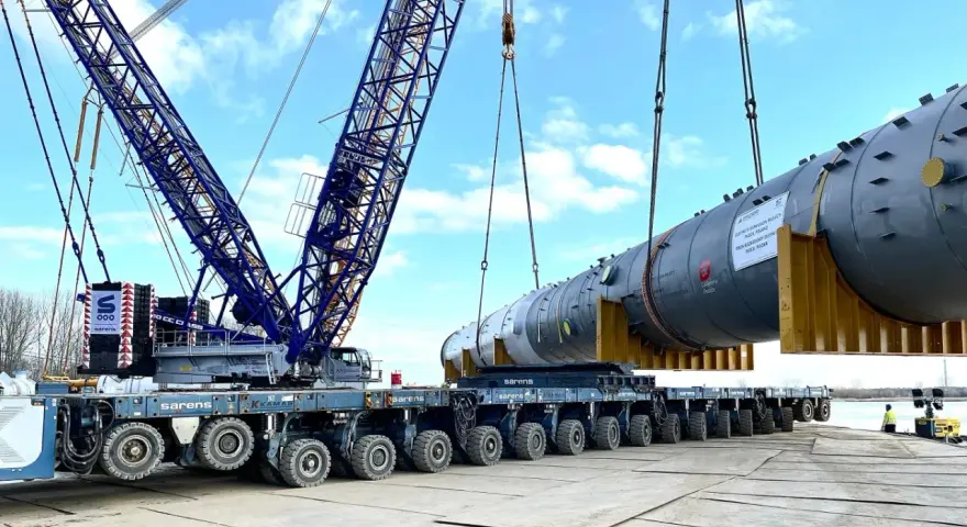 Największy transport w Polsce: potężny dźwig Sarens podnosi ogromny element instalacji na wielokołową platformę.