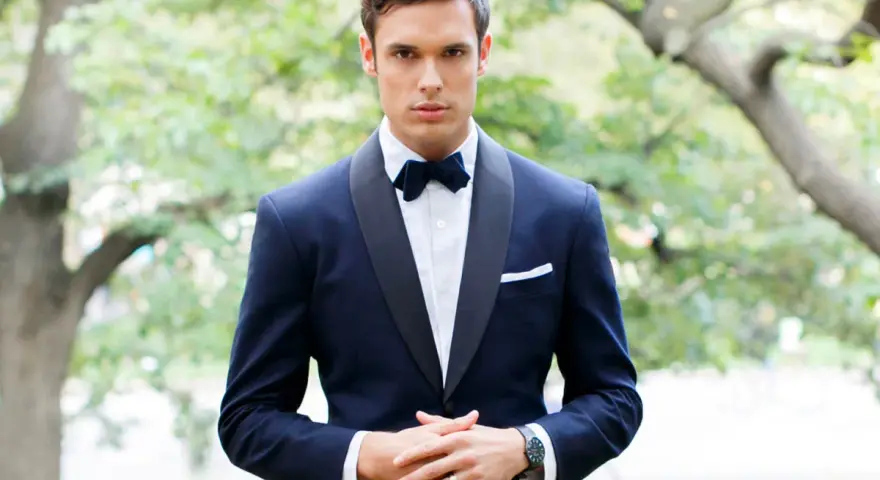 Uomo con smoking blu scuro, papillon e fazzoletto bianco. Il colore abito padre dello sposo è elegante e raffinato.
