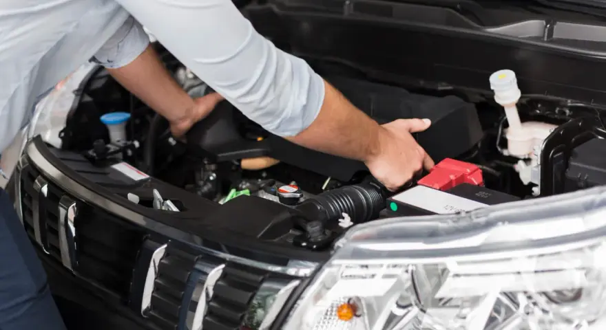 Meccanico controlla il motore per problemi al motorino d'avviamento.