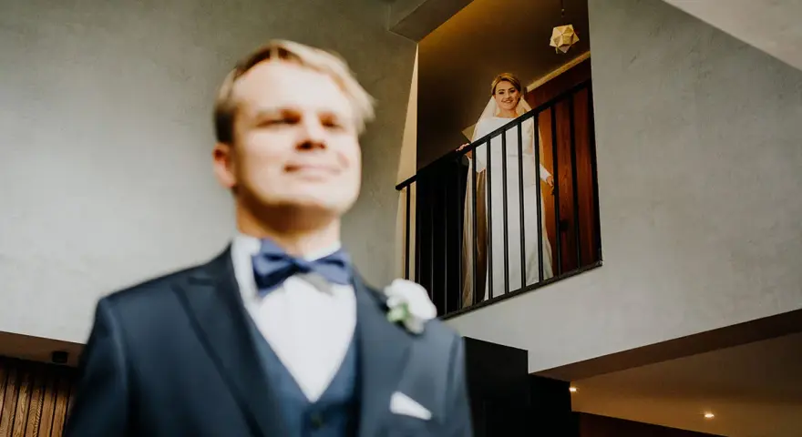 Pan młody w garniturze i panienka młoda w bieli na balkonie. Zastanawiasz się, ile bierze fotograf za wesele?
