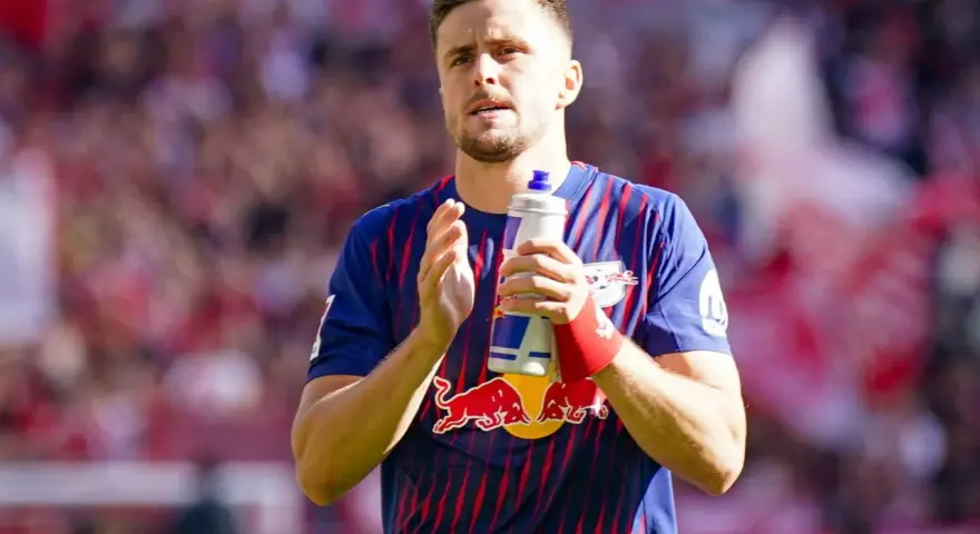 Piłkarz w koszulce RB Leipzig, jeden z zawodników 2. Bundesligi, trzyma butelkę z napojem.