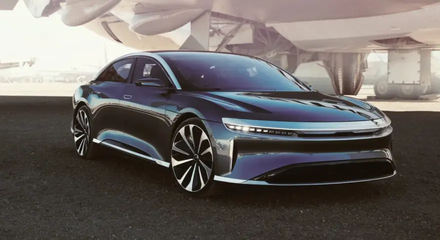 Ciemny sedan Lucid Air na tle samolotu.