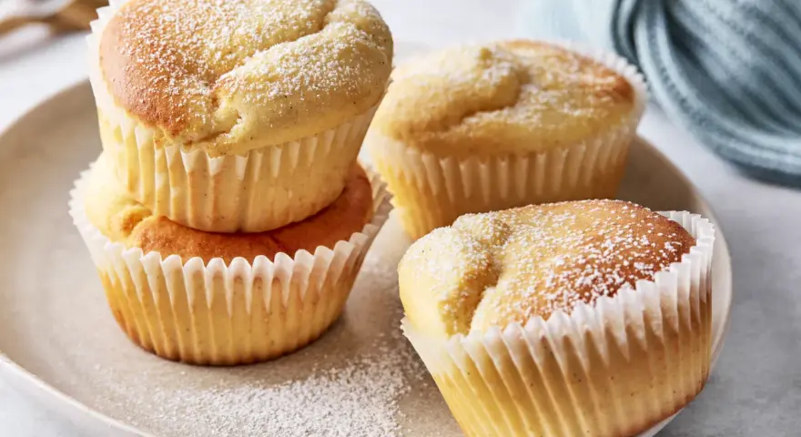 Saftige Quark Muffins, bestäubt mit Puderzucker, auf einem Teller.