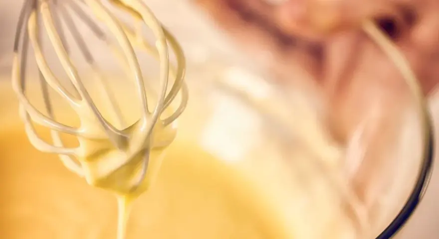 Frusta da cucina ricoperta di pastella per fritti, pronta per creare delizie croccanti.