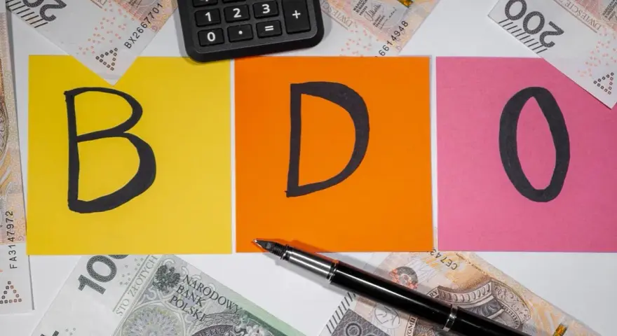 BDO - litery na kolorowych kartkach, obok kalkulator i polskie banknoty. Kto nie musi, niech nie liczy.