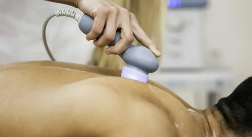 Physiotherapeutin behandelt Rückenschmerzen mit Ultraschall. Die Behandlung lindert Schmerzen nach Verletzungen.
