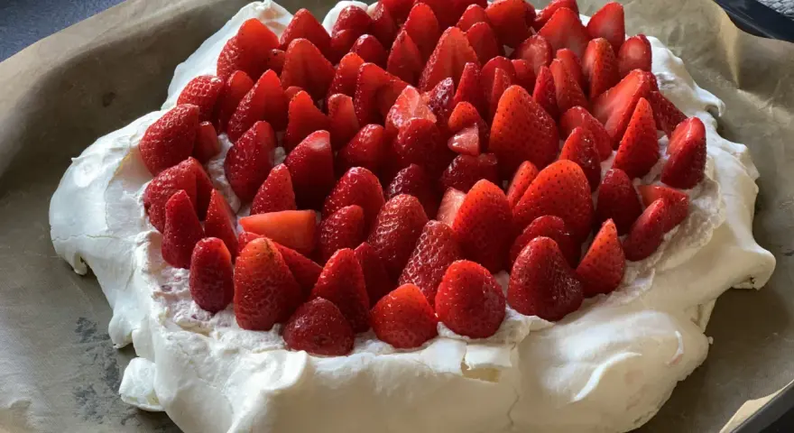 En stor pavlova i långpanna, täckt med vispgrädde och massor av färska jordgubbar. Perfekt för sommarens firanden!