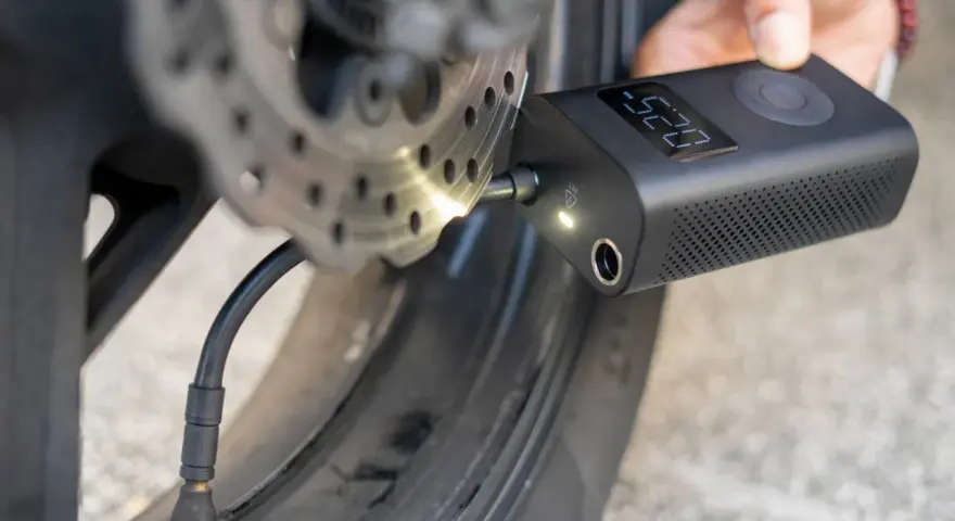 Gonfleur de pneu sans fil connecté à la valve d'une roue de moto, affichant la pression.