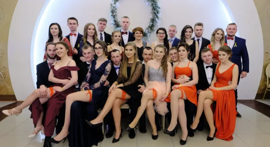 Uczniowie na studniówce, dziewczyny w sukniach, a jedna z nich ma widoczne czerwone majtki na studniówkę.
