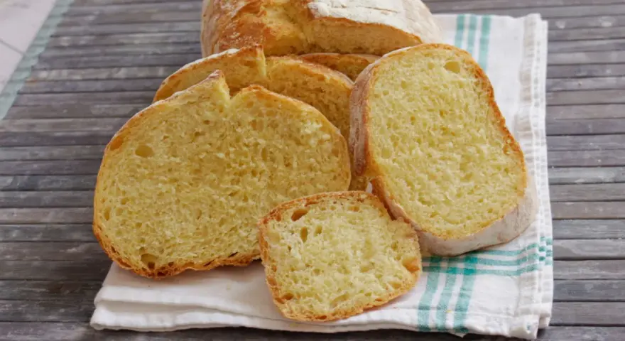 Fette di pane di semola dorato, con la crosta croccante e la mollica soffice, su un canovaccio a righe.