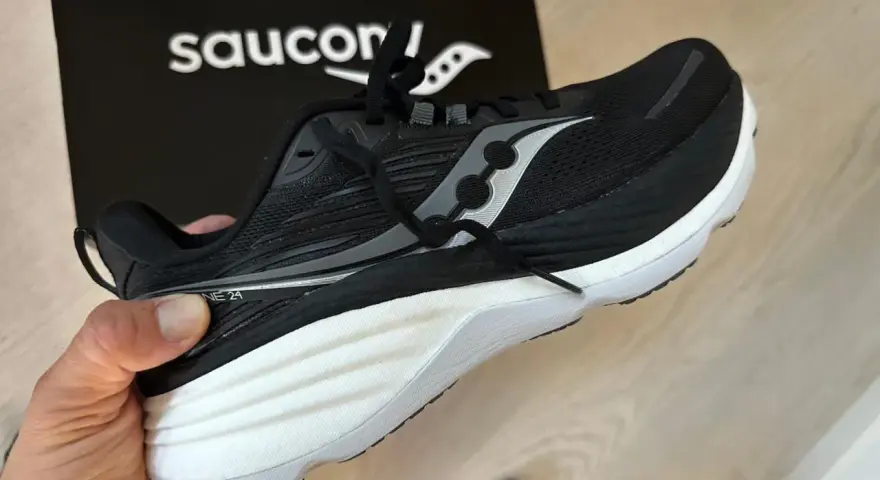 En svart Saucony löparsko, modell Guide 24, hålls upp. Denna sko är designad för att ge stöd och stabilitet, vilket är viktigt för att förstå vad pronation betyder för löpare.