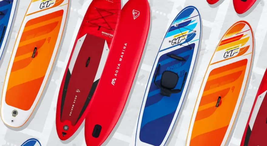 Bunte SUP-Boards, auch Stand-Up-Paddleboards genannt, liegen nebeneinander. Sie sind für Wassersportler gedacht.