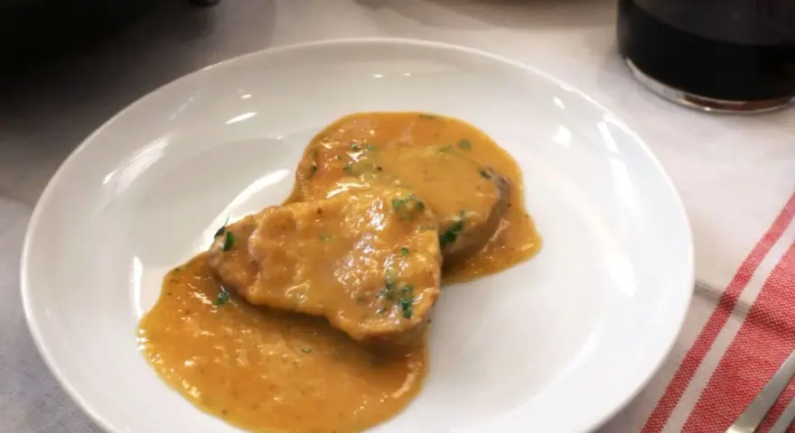 Dos medallones de solomillo al ajillo en una salsa cremosa, servidos en un plato blanco.